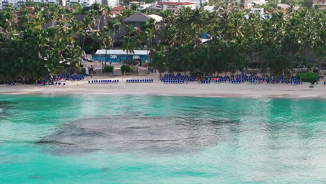 drone shot of scenery bayahibe beach during sunny day, where people enjoys vacation on clear caribbean sea shore in dominican republic