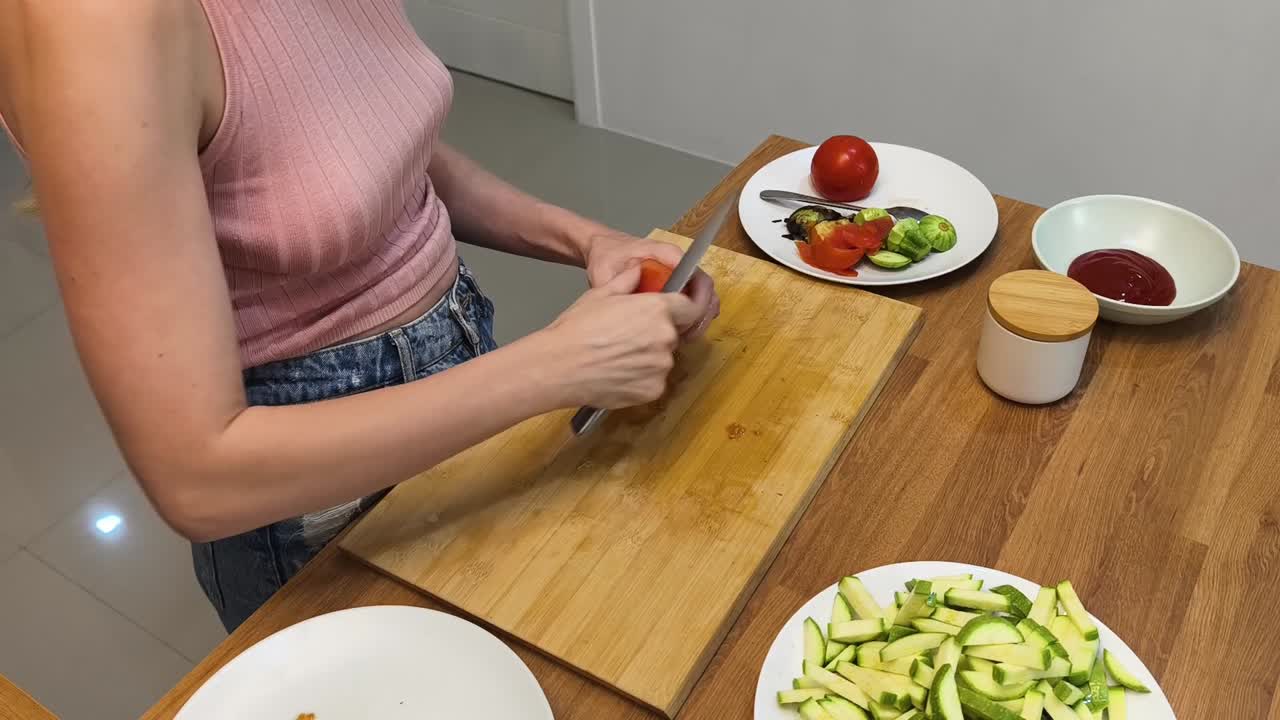 Woman cutting tomato on wooden board