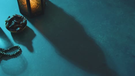 High-Angle-Tracking-Shot-of-Dates-Water-Beads-and-Lantern-On-a-Table