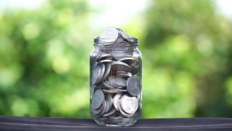 saving money coins in a glass jar. close up shot.