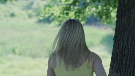 woman in yellow dress dancing by tree in summer park