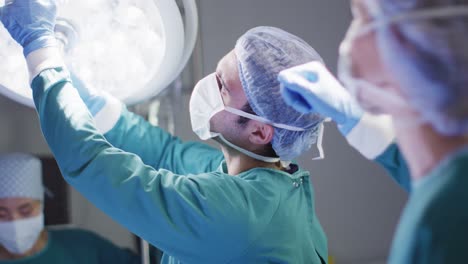 video of caucasian female surgeon and male surgical assistant preparing theatre light for operation