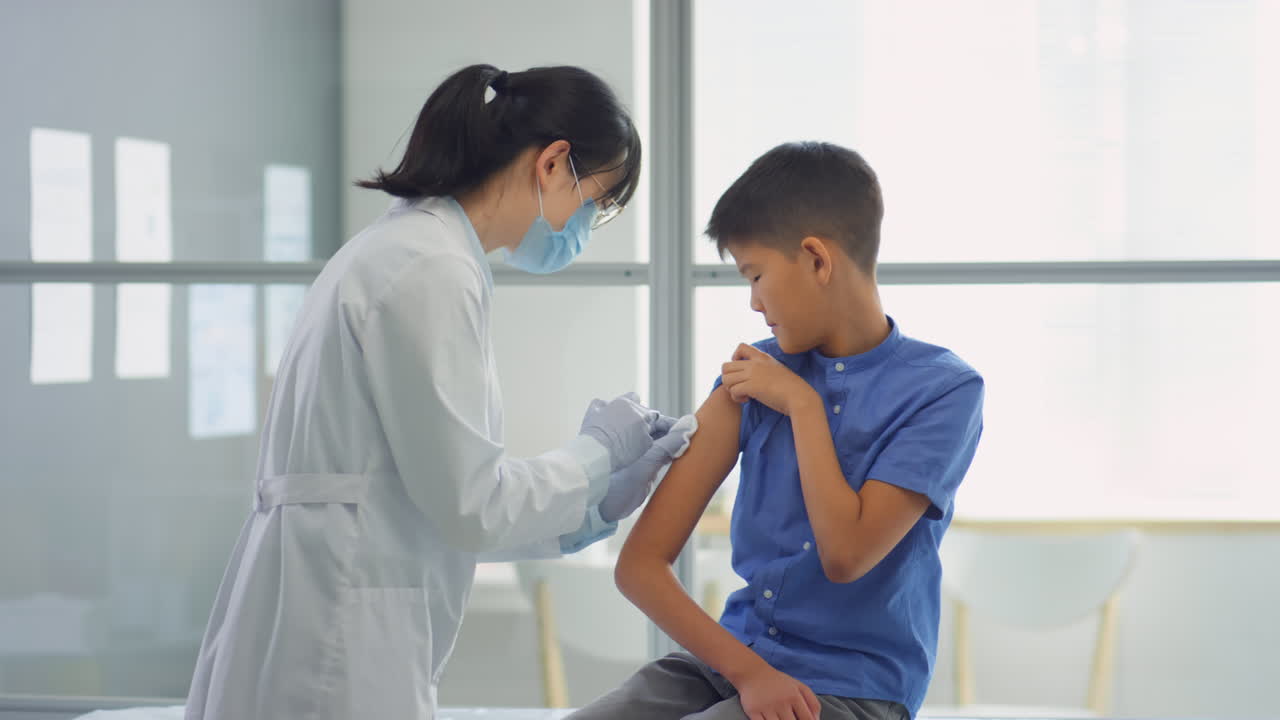 Doctor Vaccinating Asian Kid in Clinic