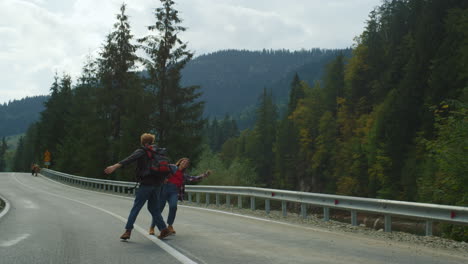 backpackers dancing mountains road. cute couple hold hands on nature travel trip