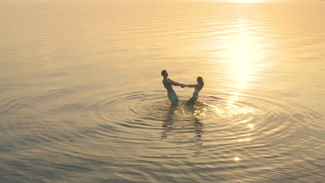 the young couple holding hands and spin in circle against the beautiful sunset