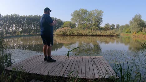 Male-Tourist-Takes-Phone-Photo-Of-Pond-At-Hanshiqiao-Wetlands,-Beijing,-China