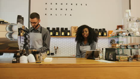 barista masculino caucásico y compañera de trabajo caucásica trabajando en una cafetería moderna