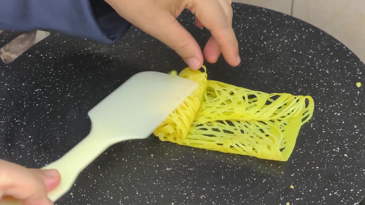 Uno chef prepara con maestria il tradizionale roti jala malese. Questa crepe a rete è fatta con pastella di farina. Presenta un colore giallo brillante e si abbina perfettamente al curry saporito
