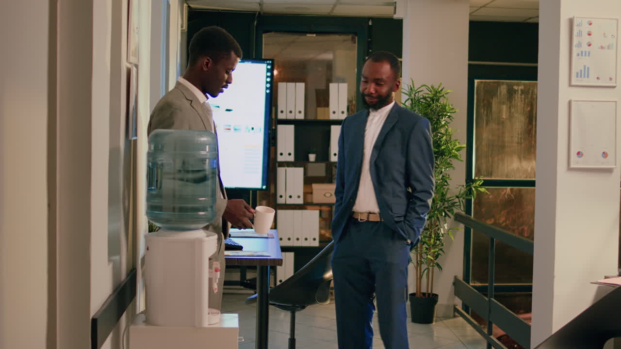 Two businessmen discussing work near water cooler in office