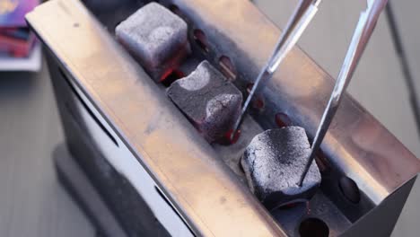 turning glowing hot hookah coal with a pliers, electric charcoal lighter