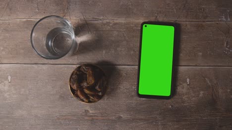 High-Angle-Shot-of-Lantern-Water-and-Dates-with-a-Green-Screen-Phone