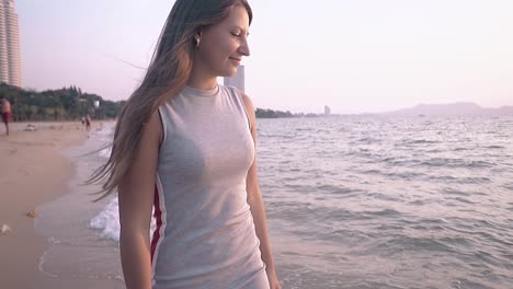 chica en vestido camina en línea de surf en cámara lenta por la noche