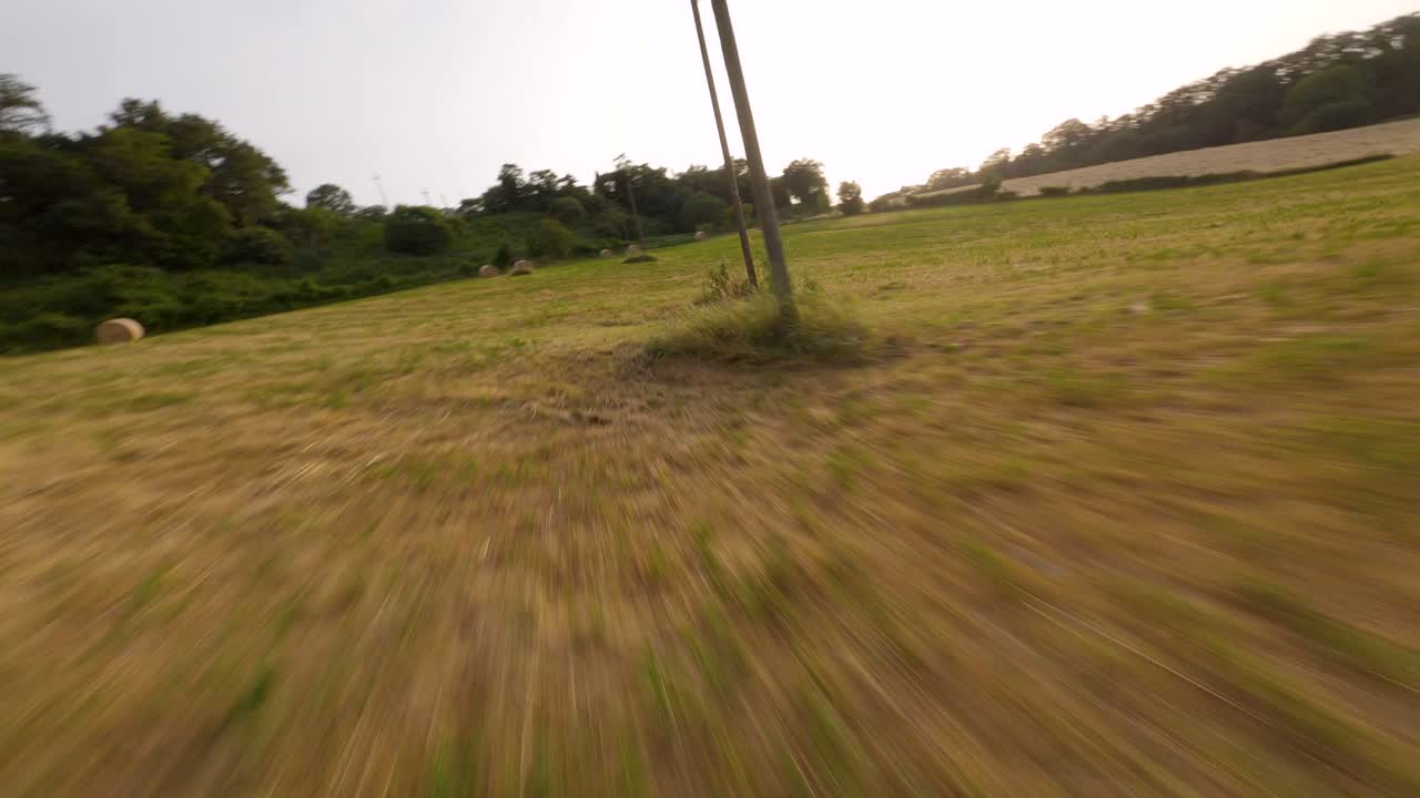 volando sobre un campo de fardos de heno con un drone fpv al atardecer