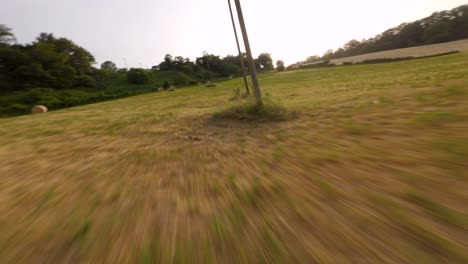 volando sobre un campo de fardos de heno con un drone fpv al atardecer