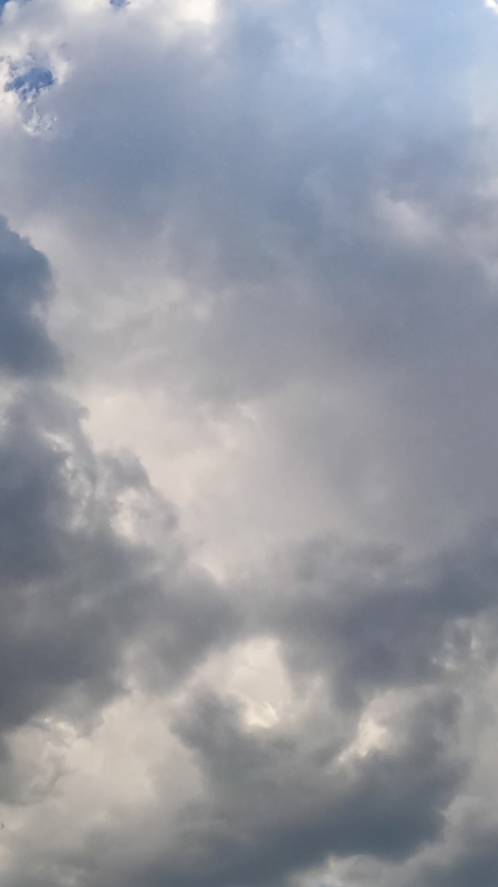 Thick grey cloudscape formation in the summer sky. Rainy clouds covering the sun. Low angle view timelapse. Vertical video