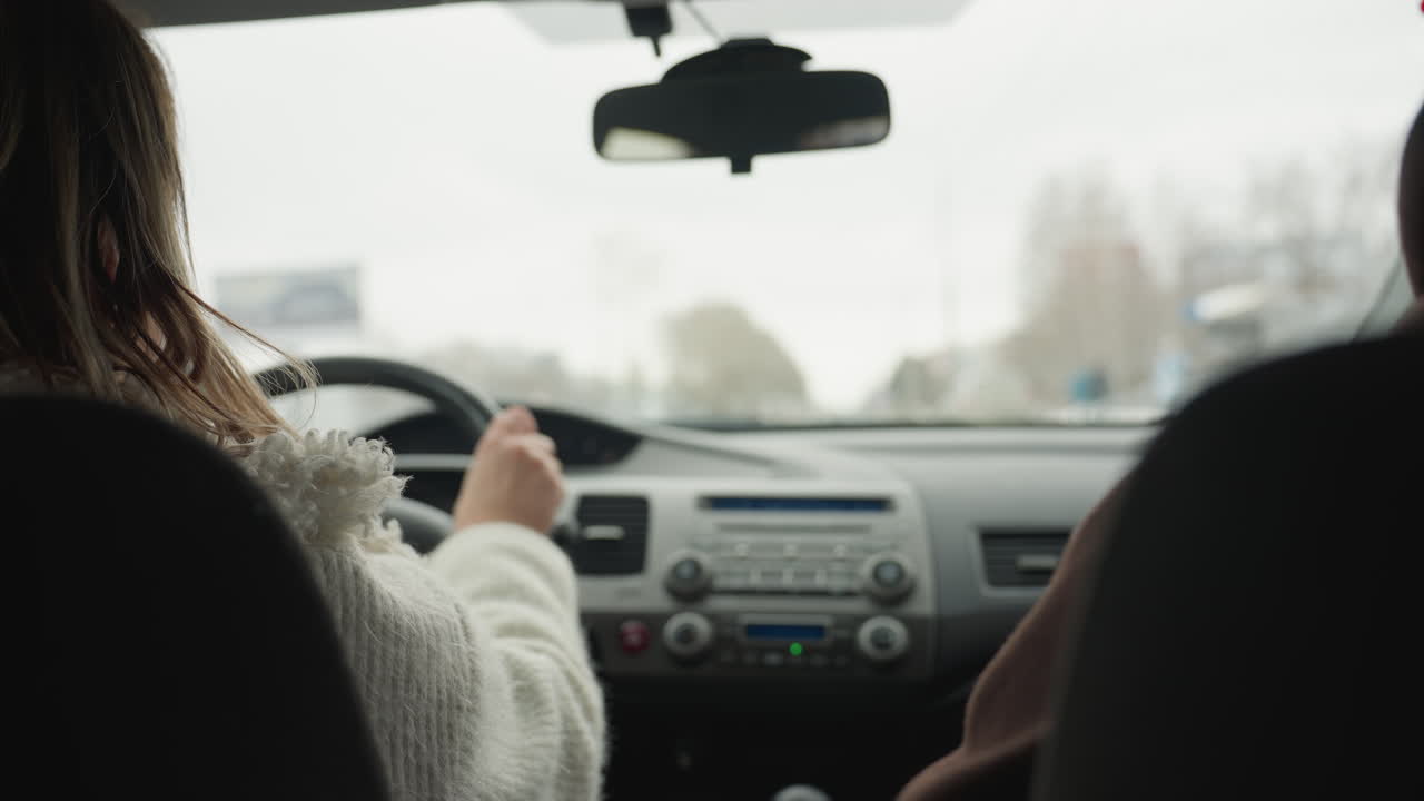 Behind view of people on road trip driving through snowy urban highway with blur surroundings and passing car seen through car window during journey with blurred signs and buildings