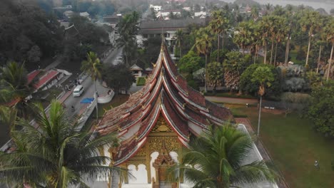 Rising-up-above-famous-Wat-Xiengthong-temple-at-luang-prabang-temple,-aerial