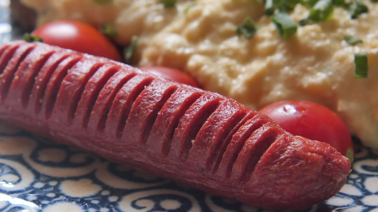 Salsiccia alla griglia con uova strapazzate e pomodorini su un piatto