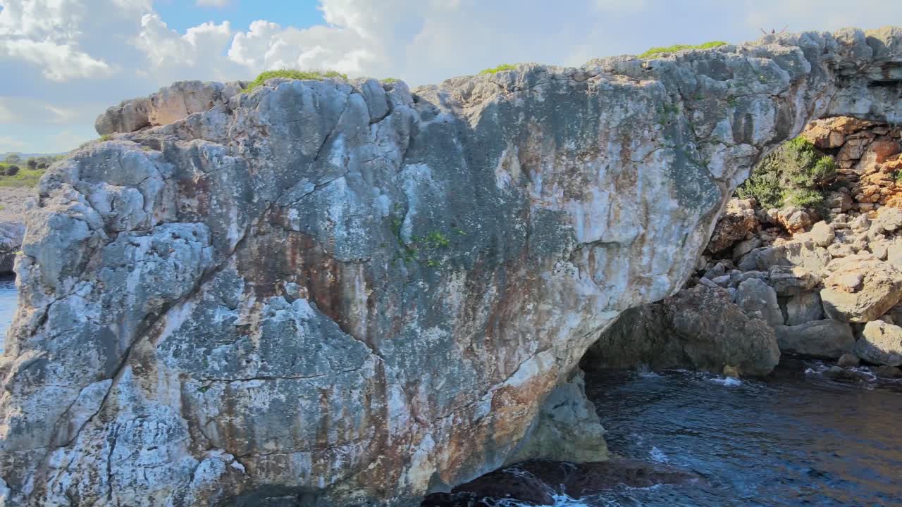 Discover the natural beauty of Cala Varques, featuring a breathtaking rock arch surrounded by clear blue waters and rugged cliffs. This serene location is perfect for nature lovers.