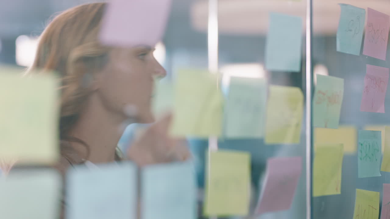 beautiful business woman using sticky notes brainstorming ideas planning strategy on glass whiteboard problem solving with creative mind map working on solution in office 4k