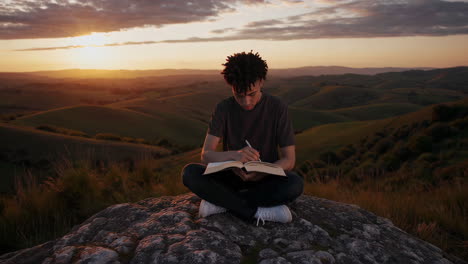 man journaling on a mountain at sunset