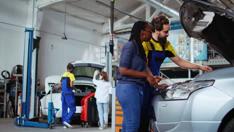 colegas en el garaje arreglan el coche de los clientes
