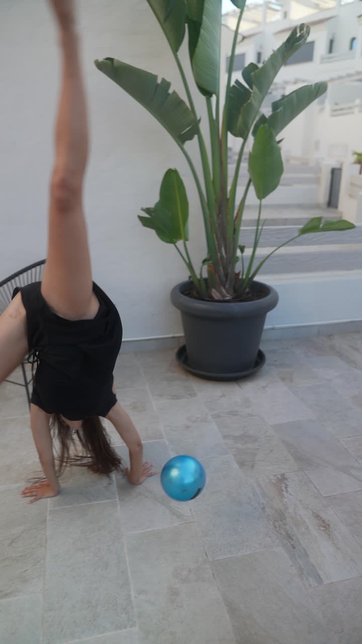 mujer haciendo ejercicios acrobáticos con una pelota en un patio