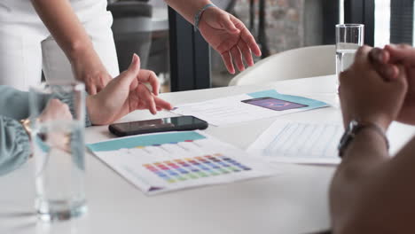 Hands-gesture-over-a-table-with-color-swatches-and-a-smartphone-during-a-business-creative-brainstor