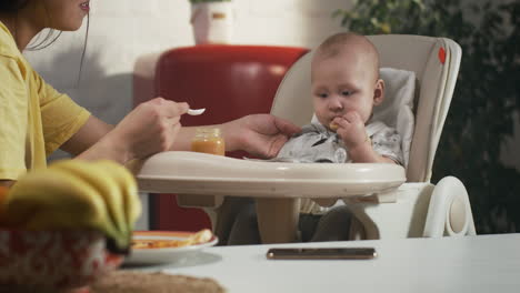 mother feeding baby in high chair