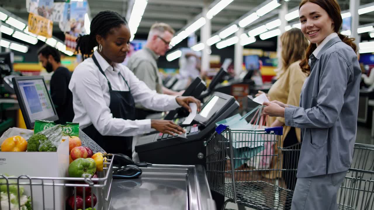 Cashier Scanning Groceries for Customers at Supermarket Checkout