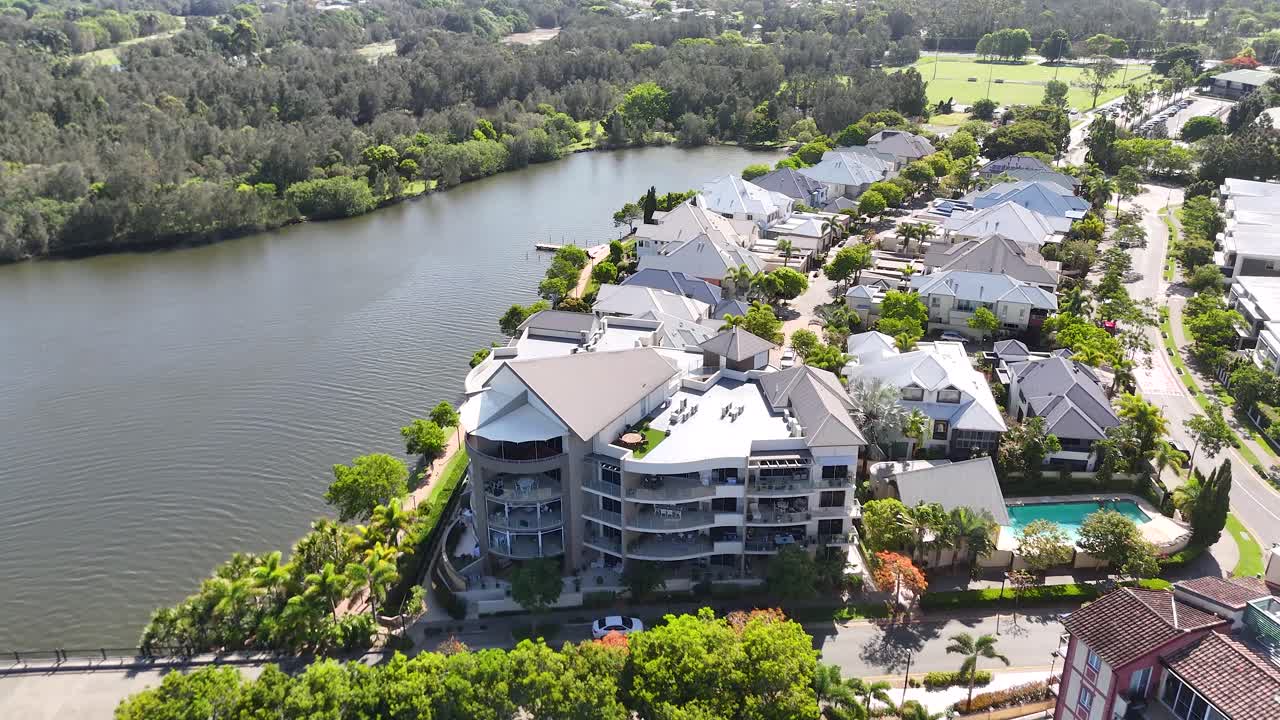 Un dron planea sobre un paseo marítimo junto al lago, un puente y unos coloridos apartamentos frente al mar a plena luz del mediodía