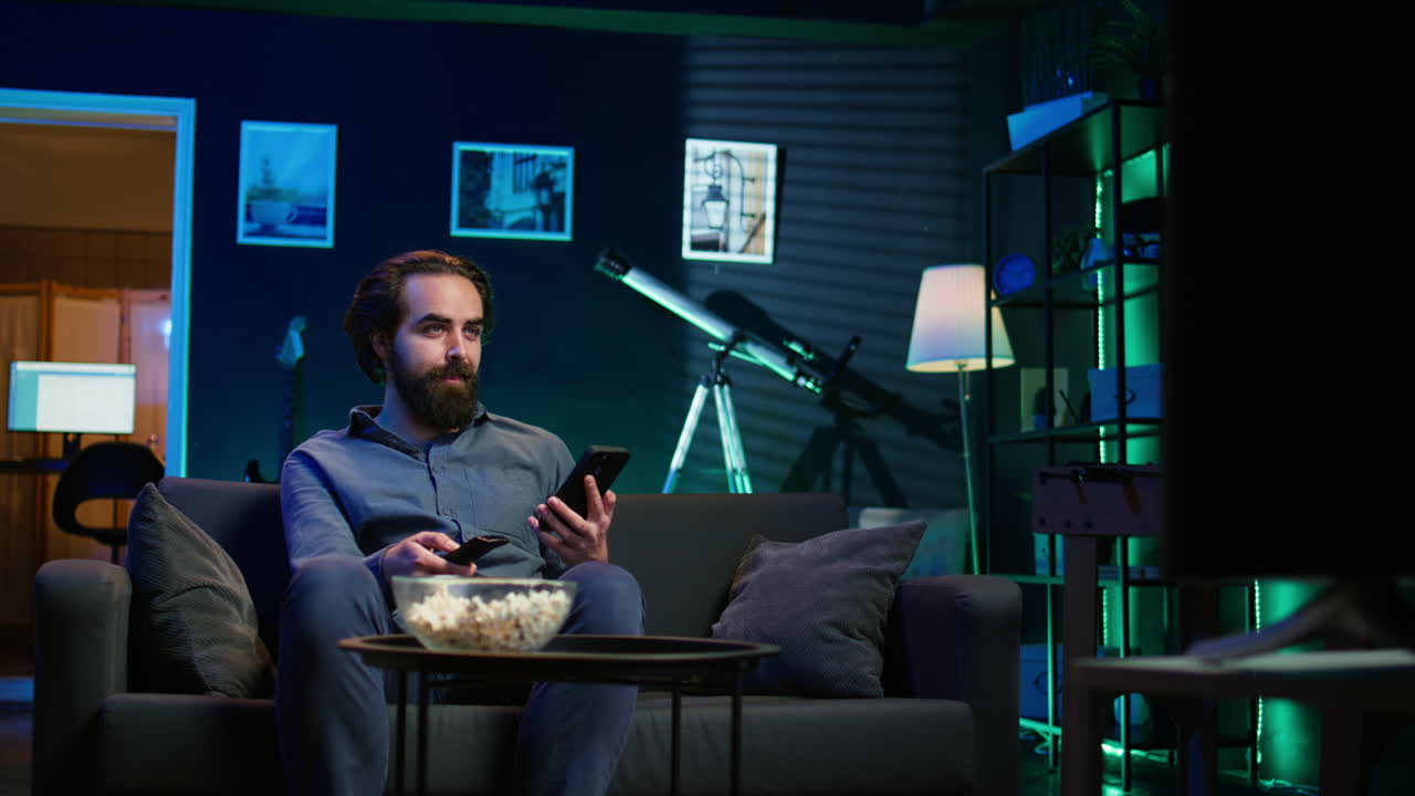 hombre feliz sosteniendo el control remoto hablando en su teléfono inteligente