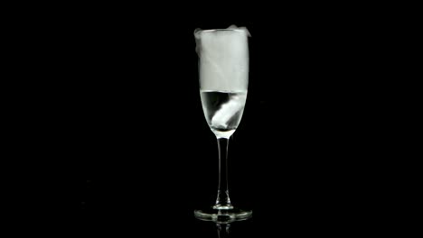 champagne flute with smoke and liquid on black background