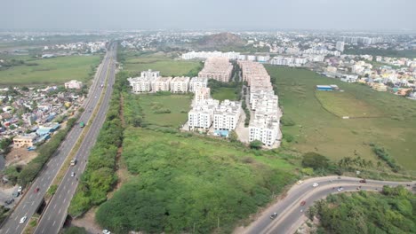 Aerial-Drone-Shot-Of-Buildings-In-A-Vast-Green-Area-Near-Highway