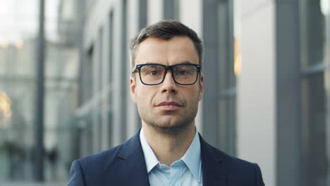 close up view of smiling businessman in glasses in the street and looking to the camera