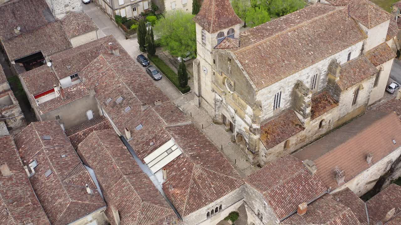 Clip video di un drone che sorvola la chiesa di Saint-Dominique e le case medievali circostanti a Monpazier. Vista aerea panoramica della storica architettura bastide e della disposizione della città nella Dordogna, Francia.