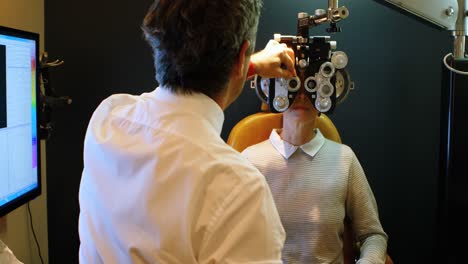 optometrist examining patient eyes with phoropter 4k