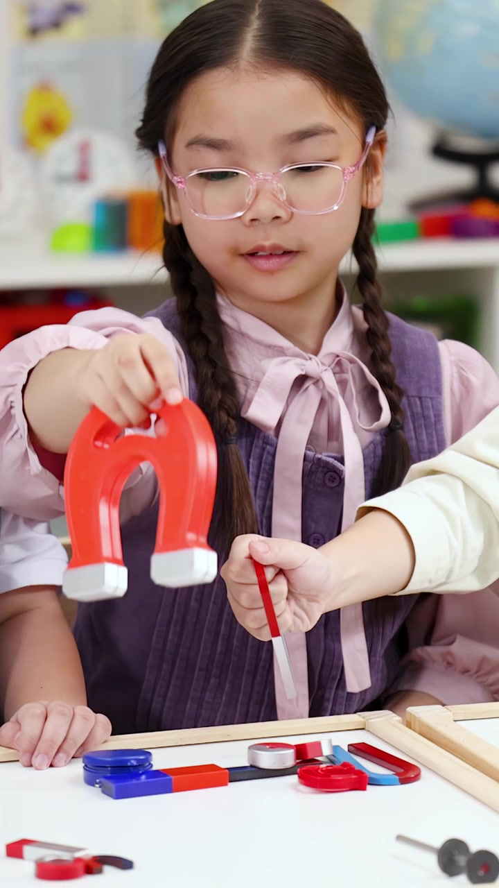 Siswa yang fokus menggunakan magnet untuk percobaan sains di ruang kelas sekolah dasar yang cerah dan penuh warna