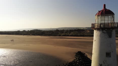 Talacre-lighthouse-golden-Wales-coastline-shimmering-low-tide-sunrise-aerial-pull-away-view