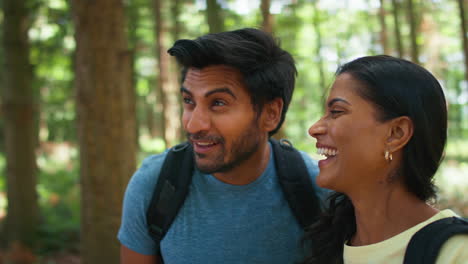 couple with backpacks hiking or walking through woodland countryside in summer enjoying nature