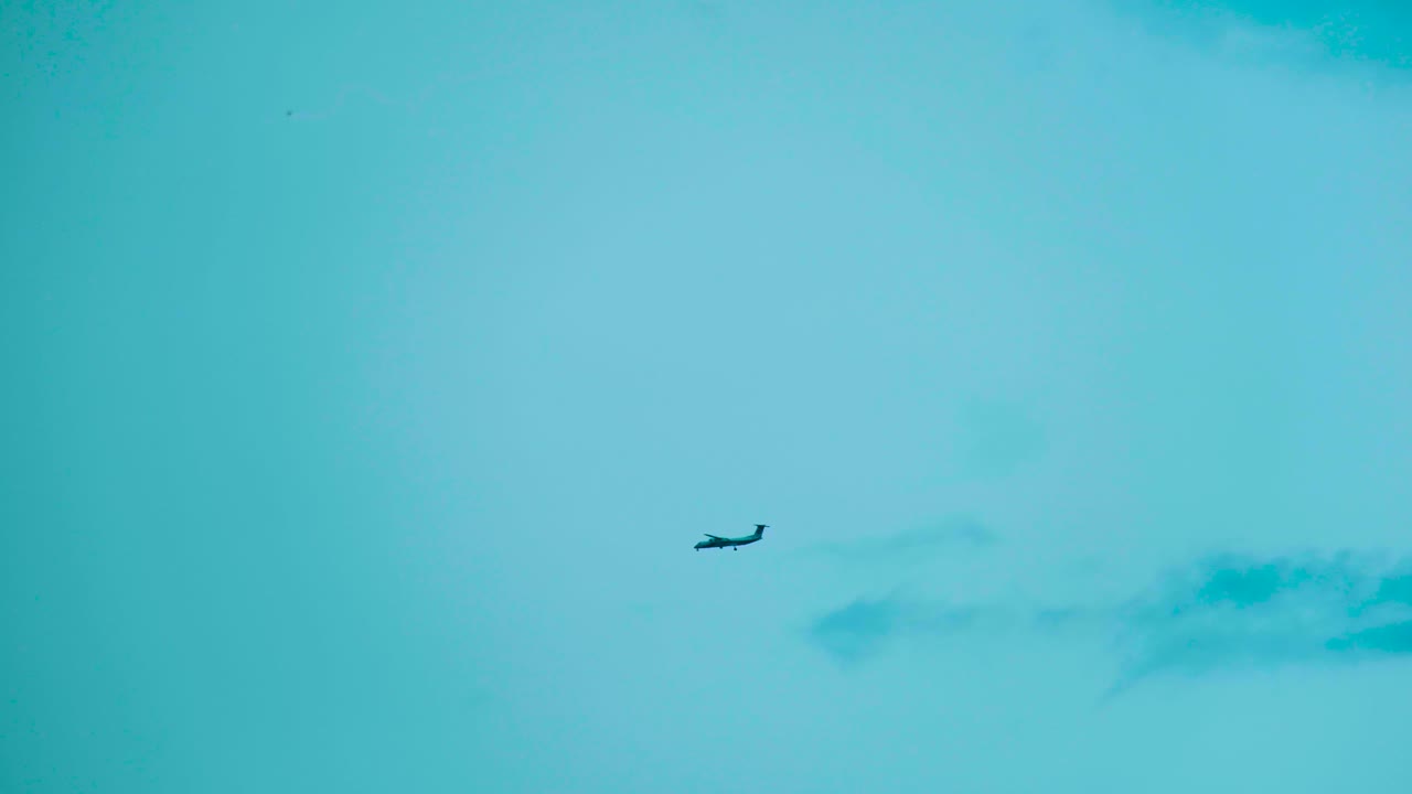 Silhouette of distant plane landing on blue sky background with copy space