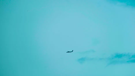 silhouette of distant plane landing on blue sky background with copy space