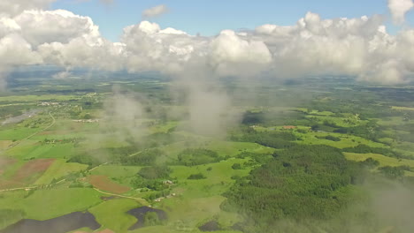 aerial - flying through clouds over green landscape on sunny day