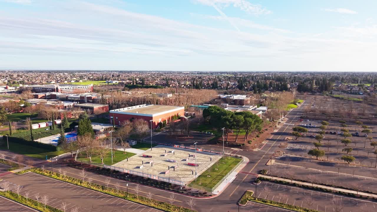 Vedute aeree rivelano il Cosumnes River College durante l'ora d'oro, dove la luce solare ambrata delinea tetti, cortili e sentieri, creando un pacifico paesaggio accademico incorniciato dall'orizzonte di Sacramento