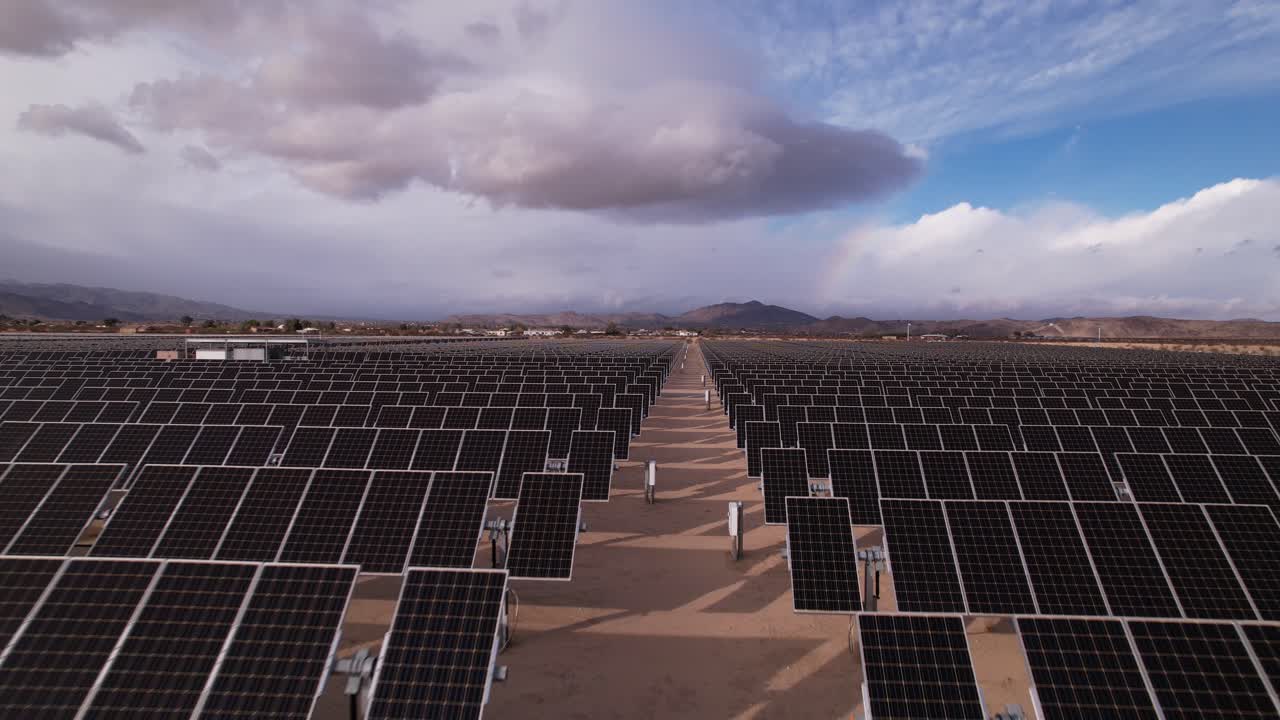 imágenes aéreas de drones del campo de paneles solares en el parque nacional del árbol de joshua en un día soleado con arco iris en el fondo, movimiento rápido hacia adelante y hacia arriba