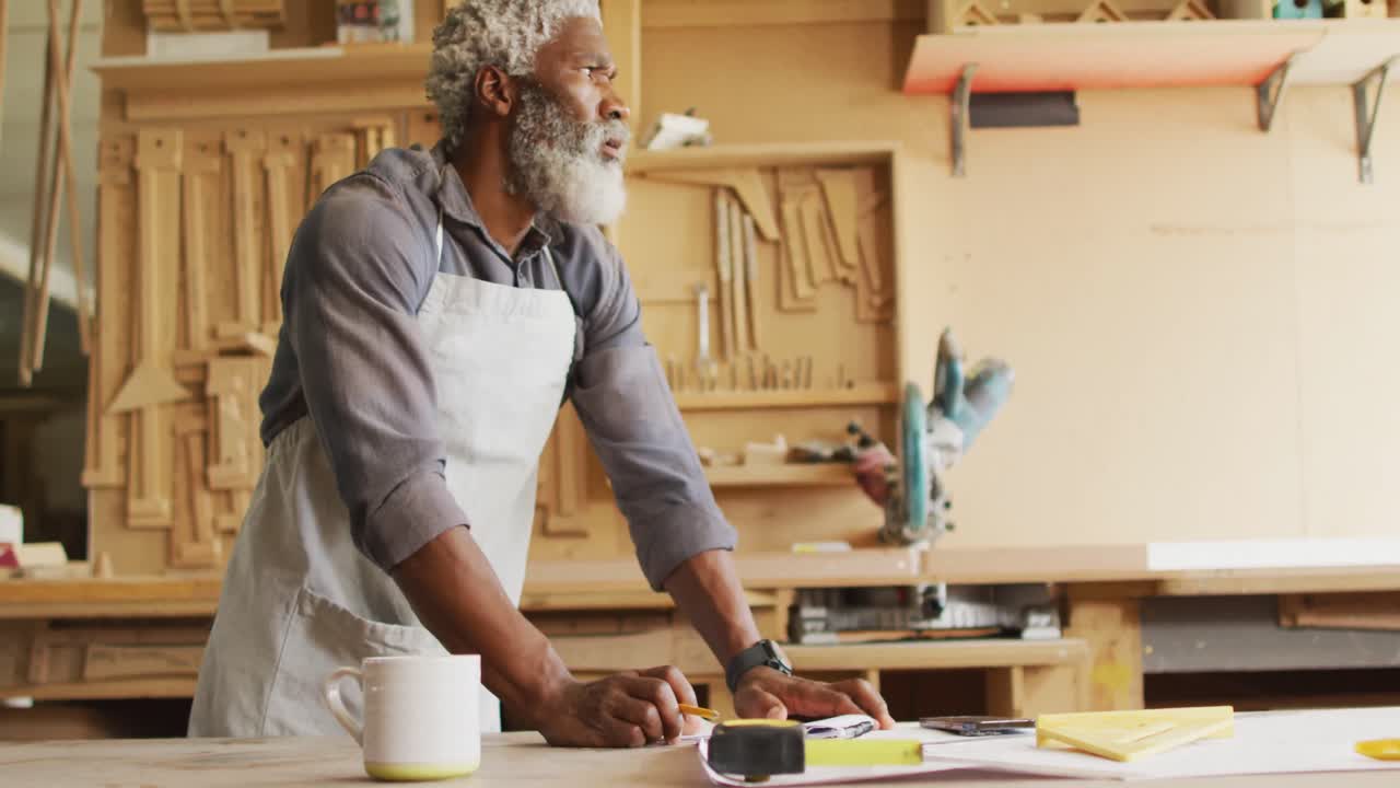 Thoughtful african american male carpenter sketching a project in a carpentry shop