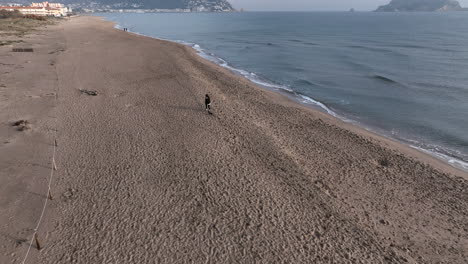 woman and miniature dachshund dog running around empty beach