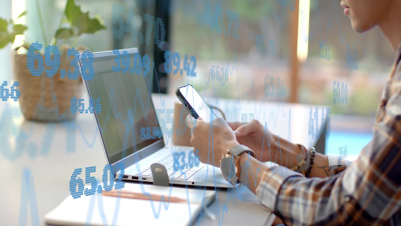 Worker reaching for phone, shifting from typing to scrolling while tracking blue finance overlays