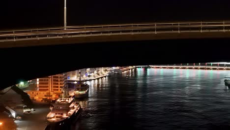 curved juliana bridge frames handelskade as cars rush by at night, aerial overview