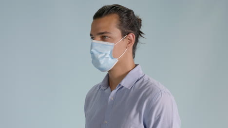 Handsome-brunette-man-putting-on-hygienic-mask